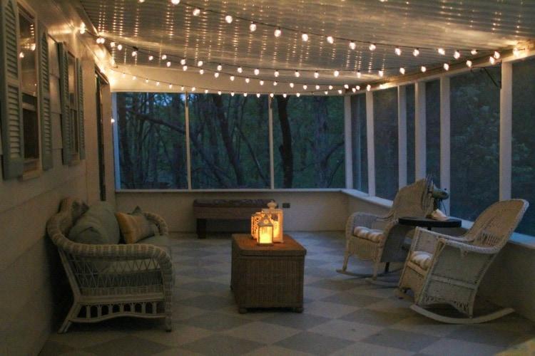 Hang string lights for enchanting ambiance in your screened porch oasis