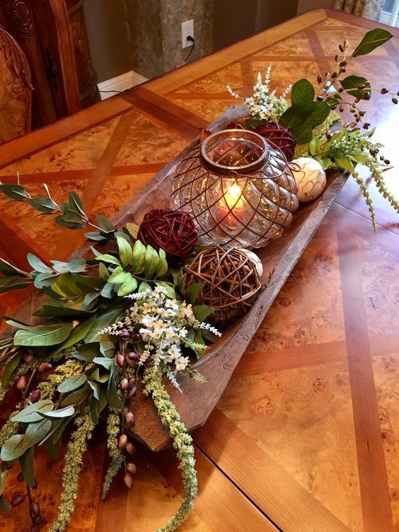 a bread bowl with wicker balls, acorns, greenery and white blooms .