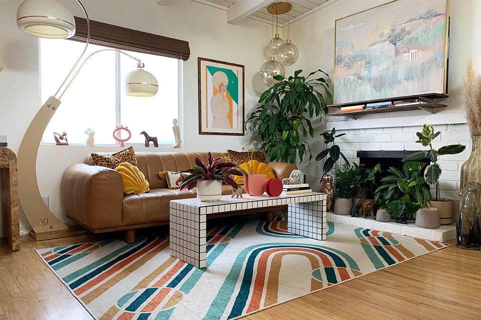 A vibrant area rug unifies the eclectic living room’s diverse elements